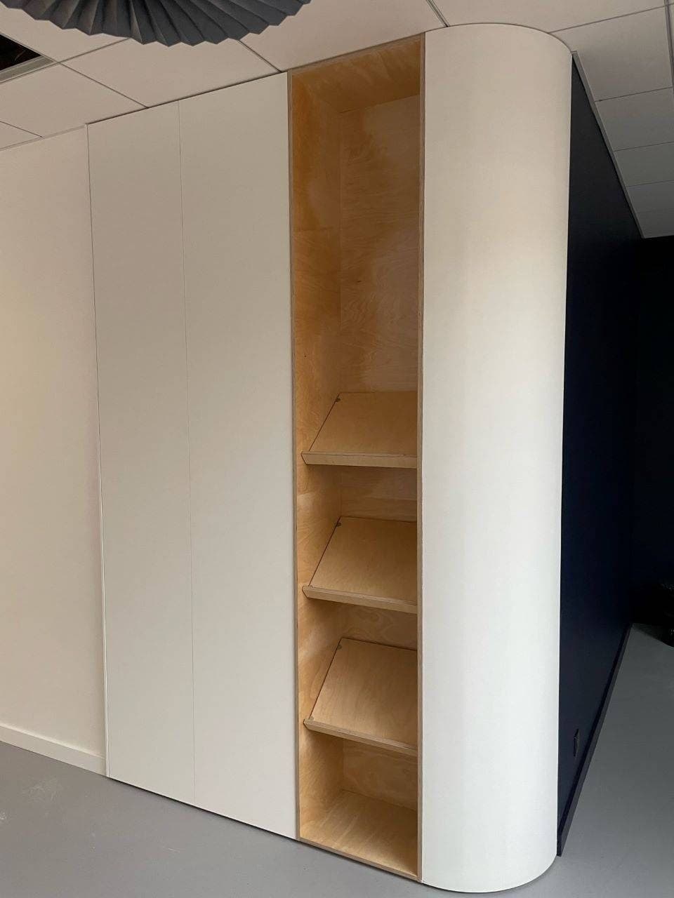Le porte-revues du couloir : des niches en bois dans un meuble blanc arrondi